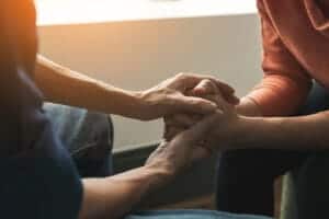 Two people hold hands while in a depression treatment program