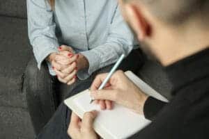 Therapist takes notes while talking to client in dual diagnosis treatment