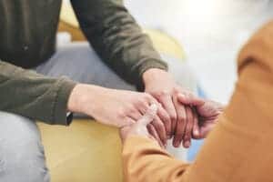 people joining hands while receiving addiction therapy services
